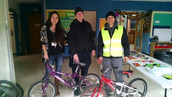 Lisa King, Ofc. Kim Alan and Beck Mugford stand with two bikes donated to the Bayview Community Center
