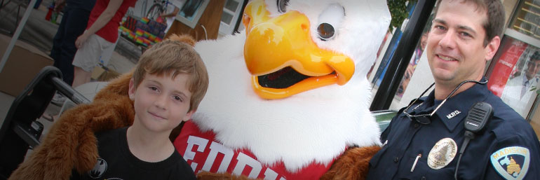 Officer and child pose with a mascot