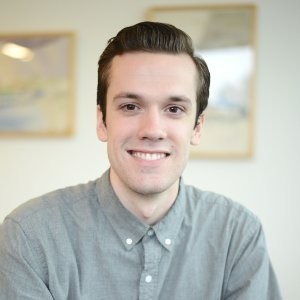 Man in a grey shirt smiles at the camera