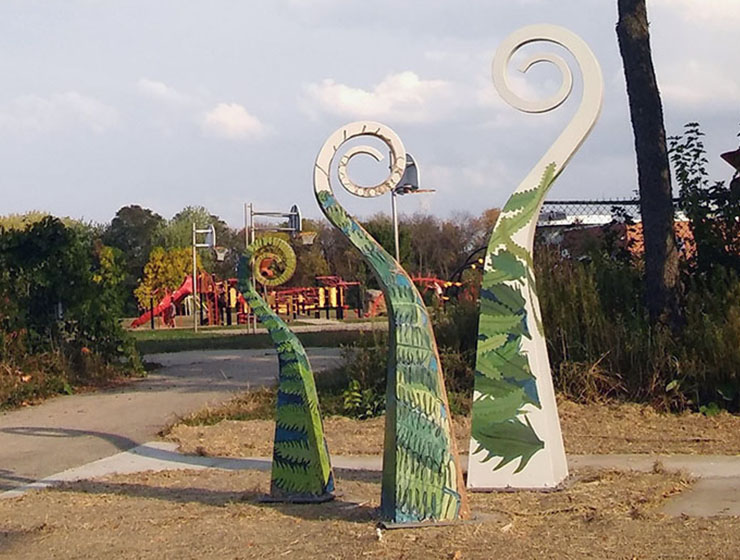 Three metal scuptures representing unfurling ferns.