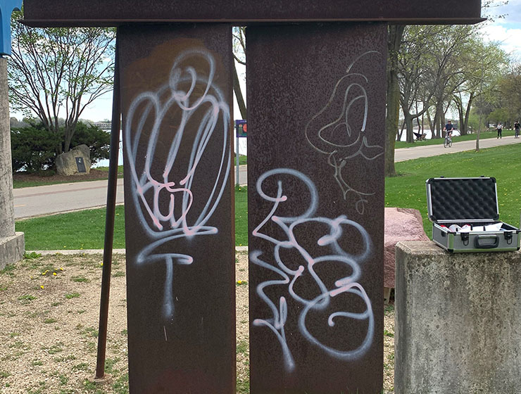 Timekeeper scuplture shown with white spraypaint graffiti.