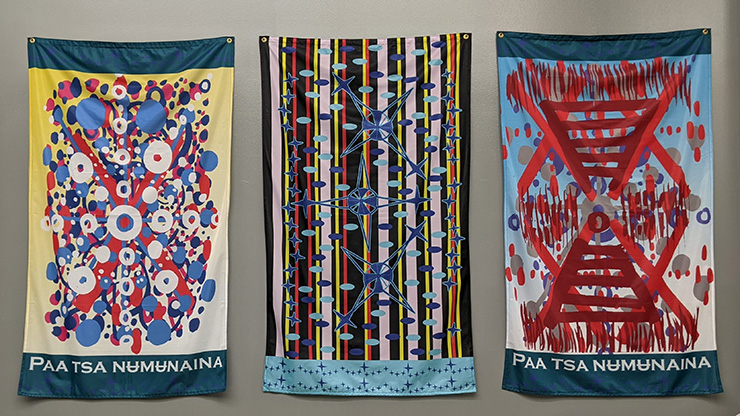 Three colorful fabric banners displayed side by side on a wall.