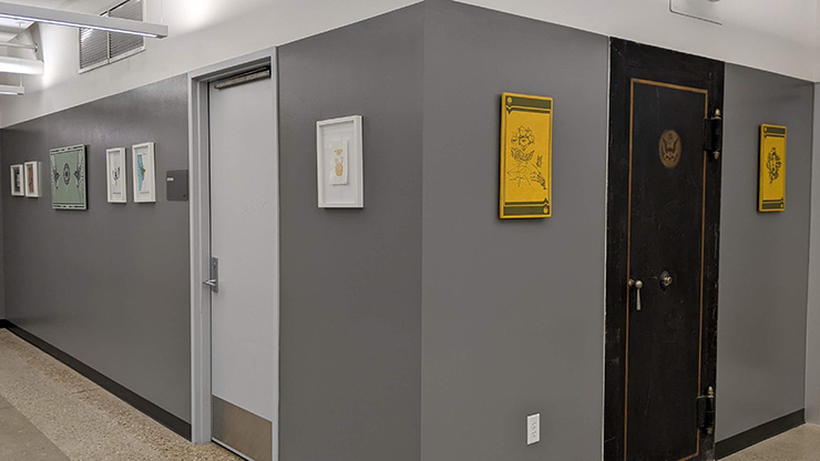 A corner of a gray walled hallway with bright white and yellow frames displaying down each hall.