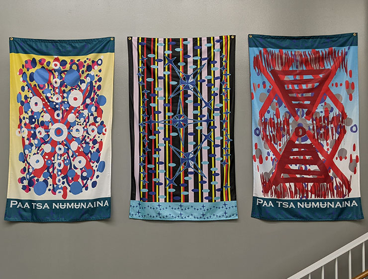 Three colorful fabric banners displayed side by side on a wall.