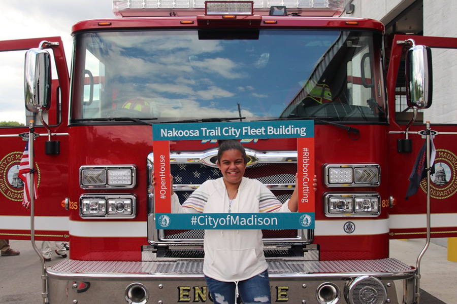 A young attendee takes a selfie with a celebratory frame in front of the electric Fire Engine 8