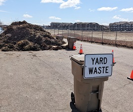 Pile of yard waste at a drop-off site with a sign stating 