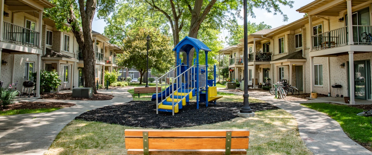 Walking paths, trees, and a playground in a courtyard of an apartment complex.