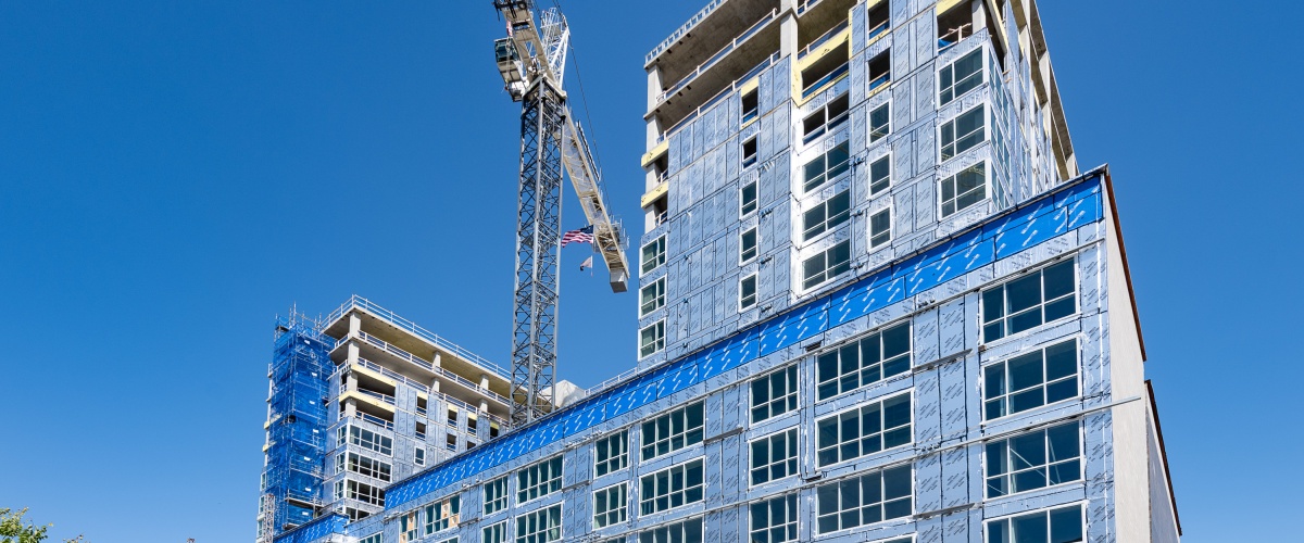 Ground view looking up at a construction crane and high-rise development