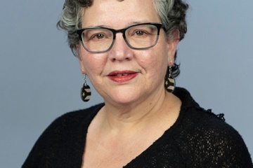 Alder Yannette is wearing a black V-neck dress. 