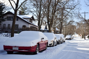 Cars parked on one side of a snowy street.