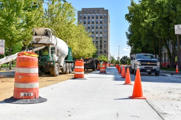 Traffic cones and cement truck on a street under construction.