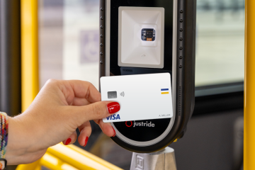 Person holding a credit card near a fare reader displaying valid. 