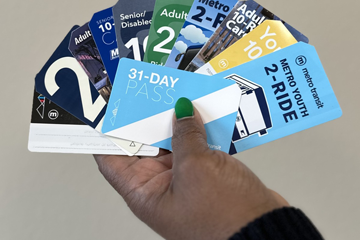 An individual holding old Metro Transit Fare cards and passes.