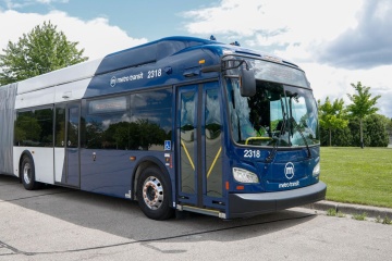 Side of blue Metro electric bus on a sunny day.