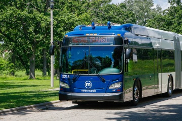 Metro Transit articulated bus traveling along a roadway beside a park.