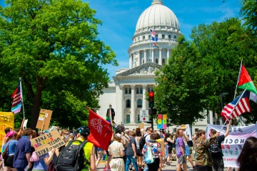 people protesting with signs in front of capitol building