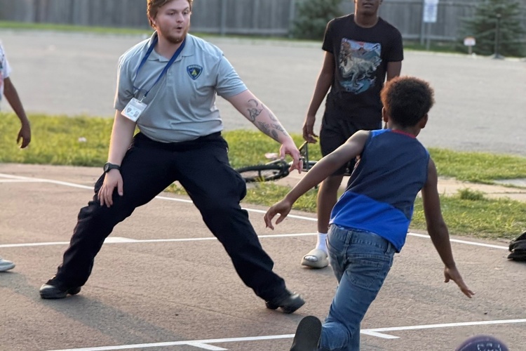 Police recruit plays basketball with children during National Night Out celebration.