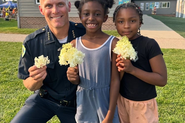 Acting Chief Patterson and kids hold flowers at National Night Out celebration.