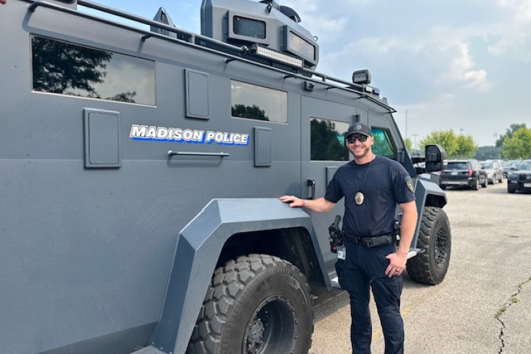 Officer stands next to SWAT vehicle at National Night Out celebration.