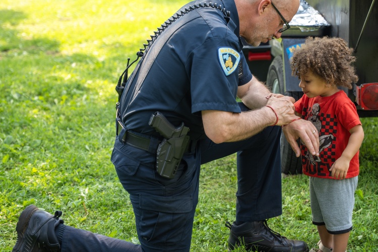 Madison police captain kneels down to interact with child at National Night Out celebration.