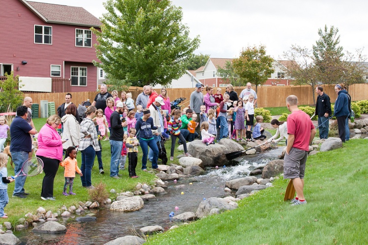 Residents gather around stream for duck race. 