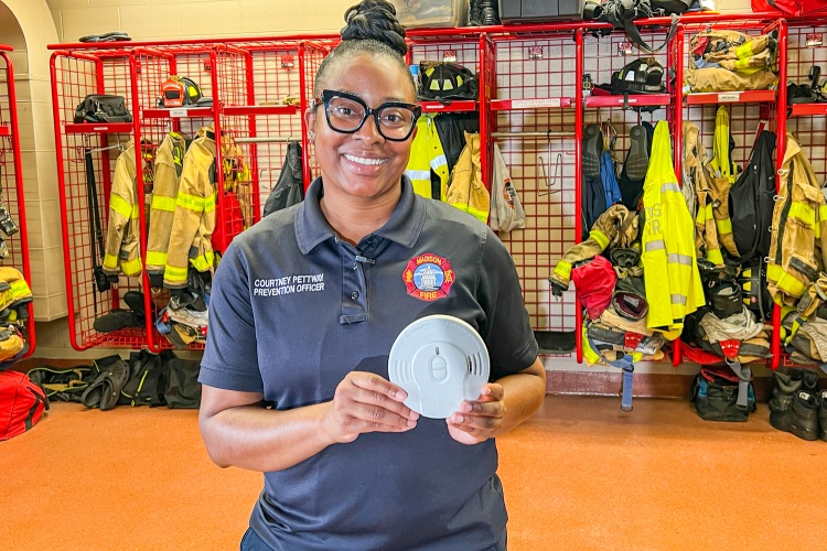A Prevention Officer holds up a smoke alarm