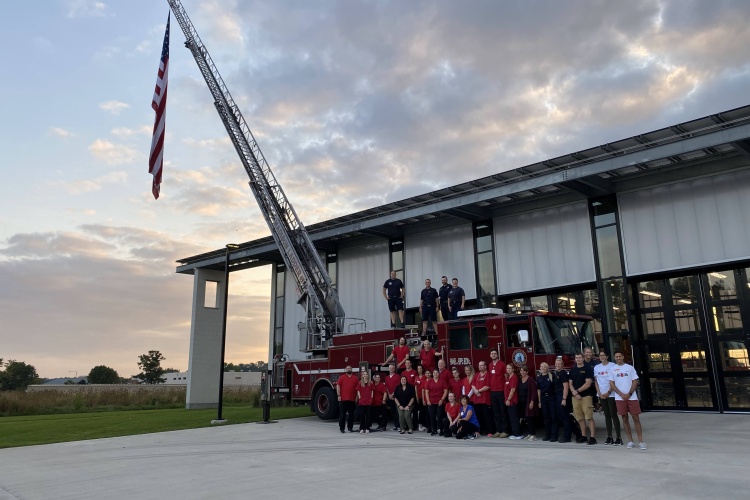 Red Cross volunteers, MFD and MPD gather around a fire truck outside the annual Never Forget blood drive