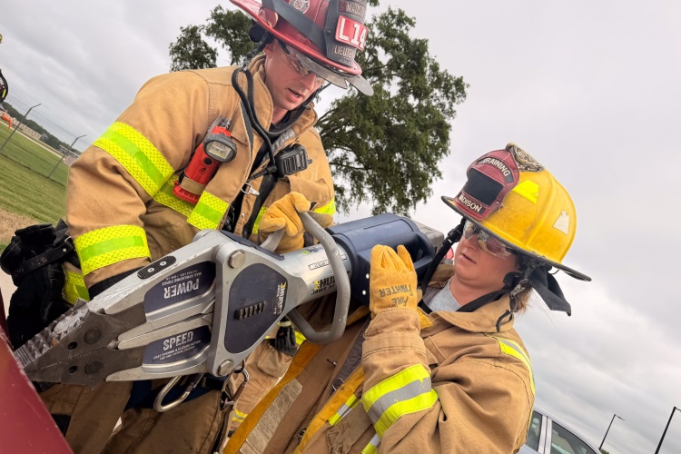 A firefighter and a medical intern hold up the Jaws of Life