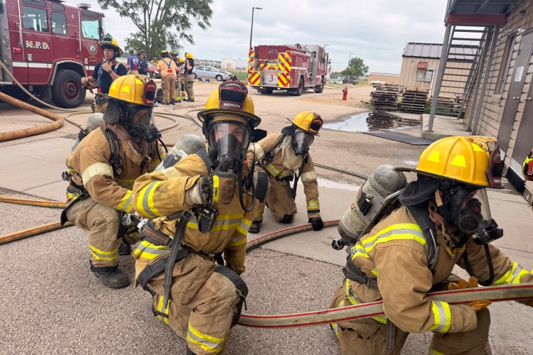 Medical intern gives a thumbs-up while advancing hose line