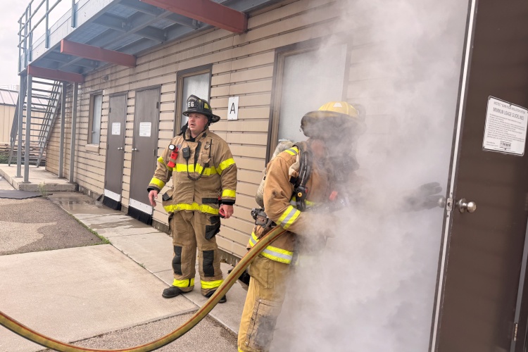 Medical intern enters a smoky room with a fire hose