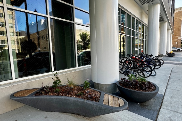 Seating with decorative planter adjacent to public bicycle racks along the State Street Campus Lake street garage.