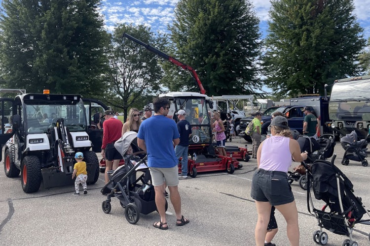 people exploring trucks and equipment at event