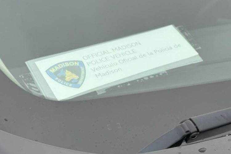 Sign hanging in car windshield of unmarked Madison Police Department vehicle.