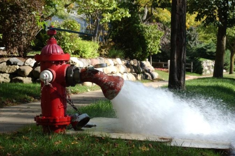 Water sprays out of a hydrant with a flushing elbow attached to it.