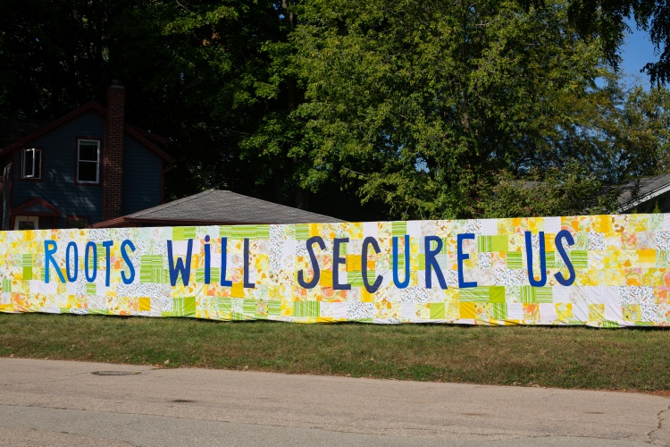 Artistic banner that says "roots will secure us"