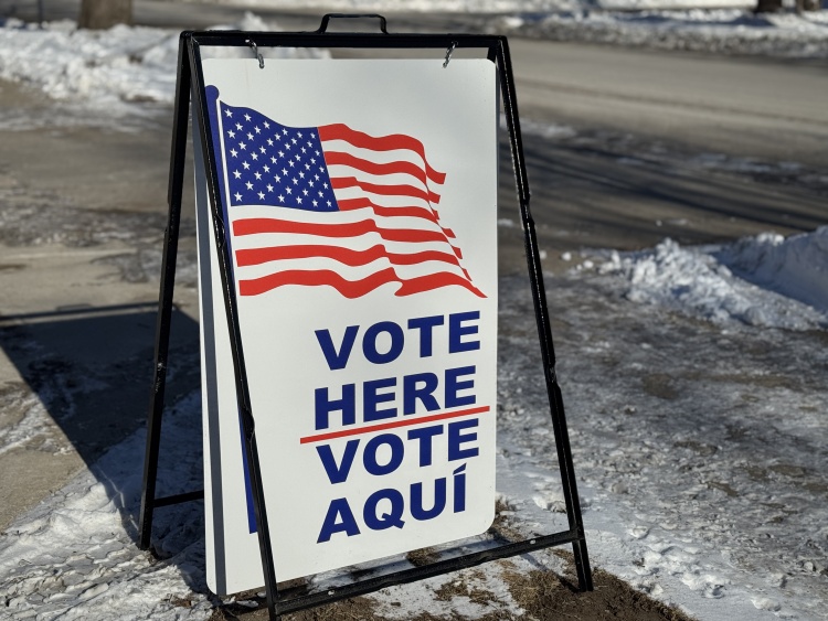 Vote Here sign on snow covered ground outside a polling place