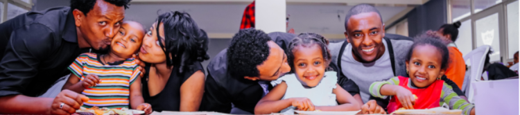 Two sets of parents embracing their children at a community dinner table.