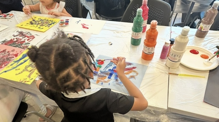 A young child works on a piece of art during an event at Avenue Square Apartments