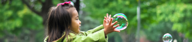 Little girl chasing bubble.