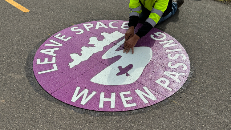 Crews install new artwork medallions on the multi-use path along Atwood Ave.