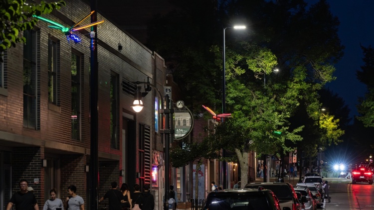 Illuminated sculptures and street banners along Gilman Street at twilight