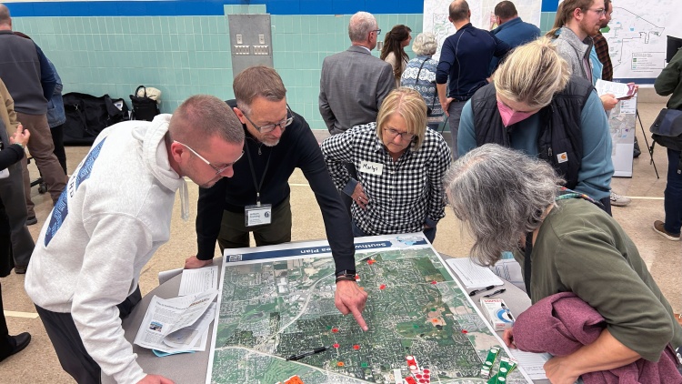 A group of residents gather around a map displayed at a Southwest Area Plan community meeting