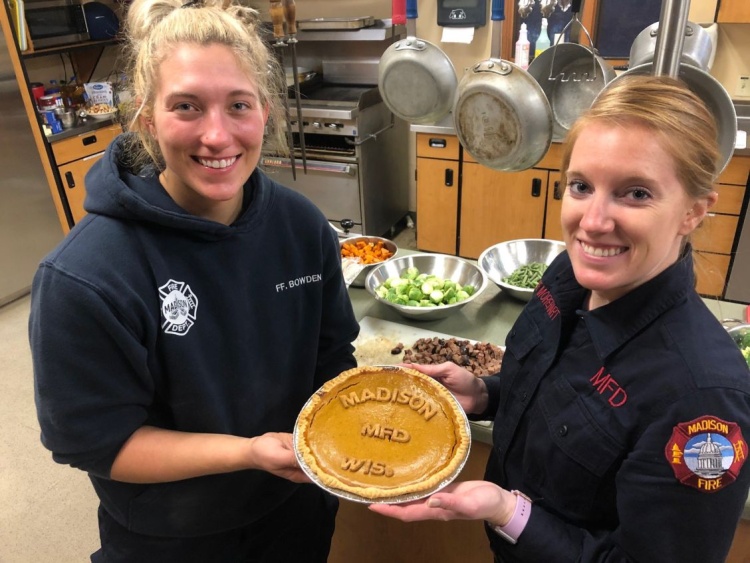 Firefighter Jessie Bowden and Firefighter Megan Morehart pose with their homemade pumpkin pie that says, "Madison MFD Wis."