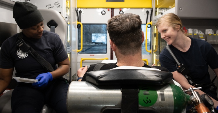Two paramedics talk to a patient in the back of an ambulance