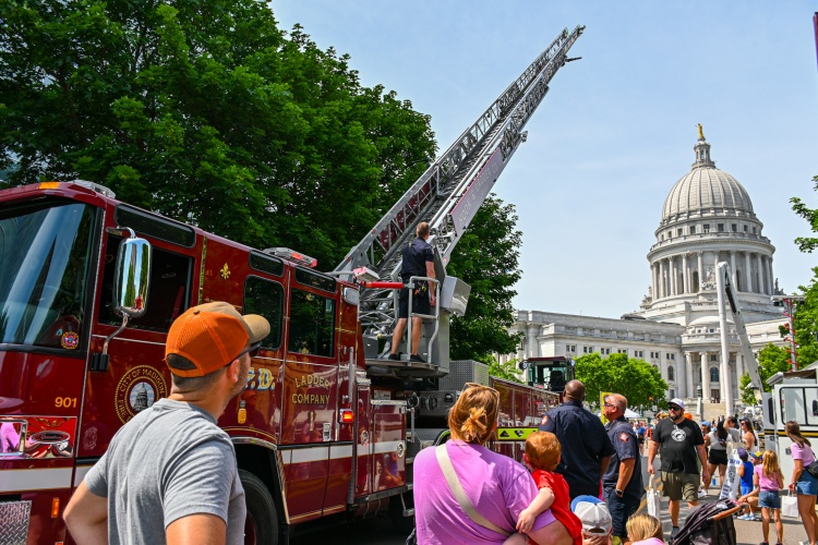 People gather around a fire truck in front of the state capitol