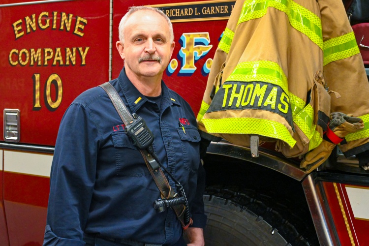 Matt Thomas stands next to Engine 10 with his turnout coat on display