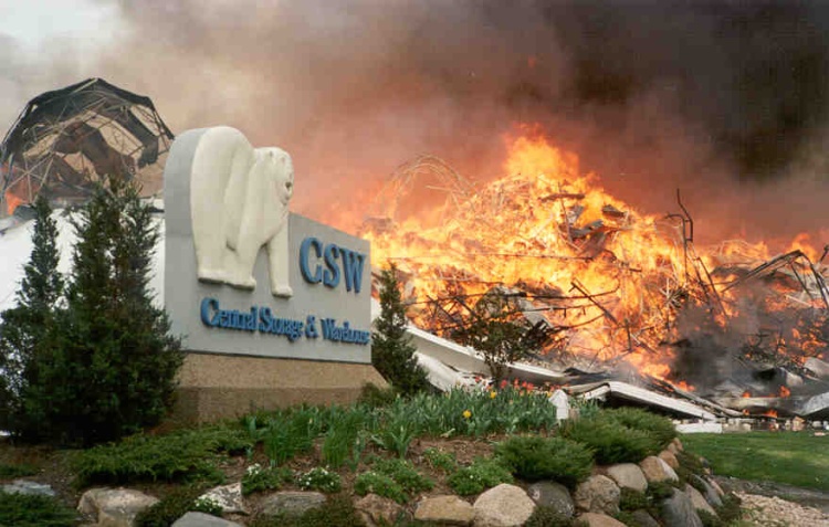 The Central Storage Warehouse polar bear sign with a large warehouse on fire behind it