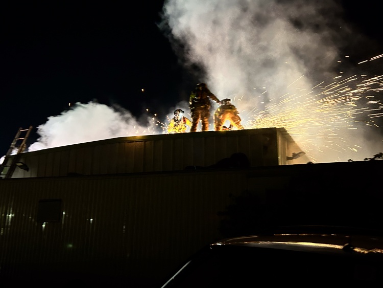 Firefighters use a circular saw to cut open the metal roof
