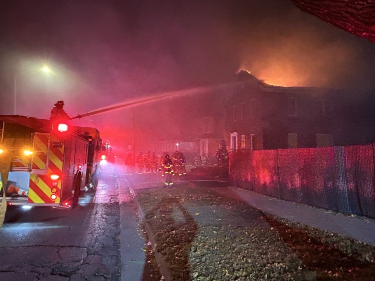 Firefighters use a deck gun to hit the main body of fire along the roofline