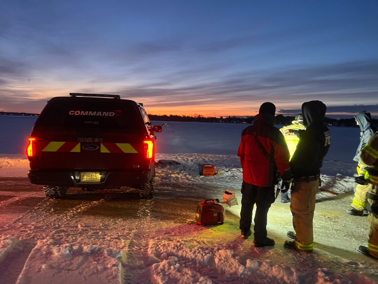 Rescuers stand beside the Command vehicle on shore